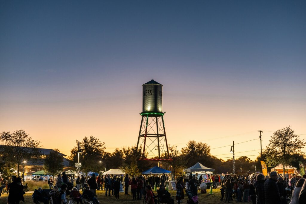 People gather near a water tower at sunset